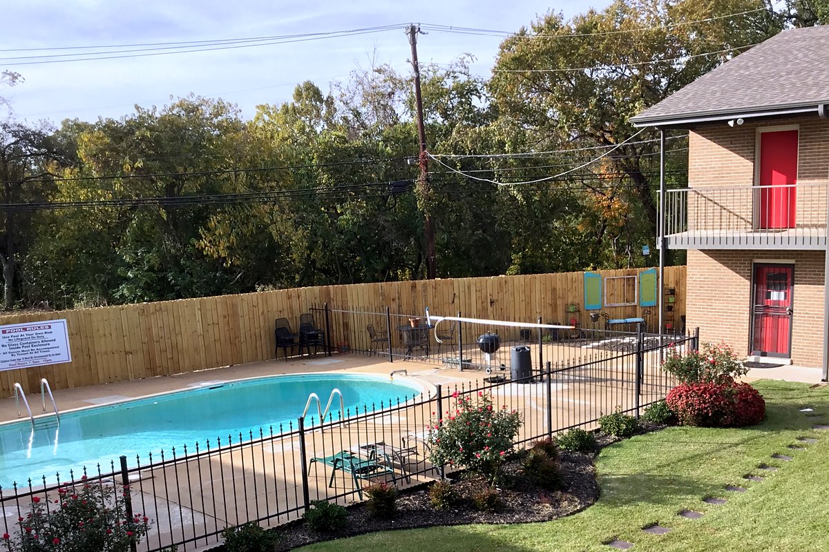 Fenced swimming pool and courtyard at Ellis Arms Apartments with the brick building and lawn