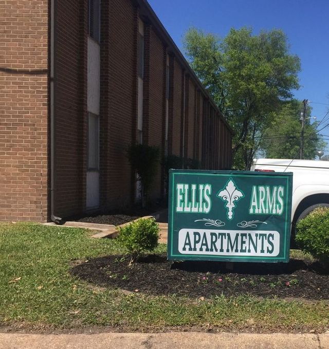 Green Ellis Arms Apartments sign in front of the two-story brick building