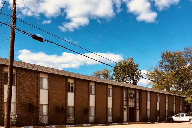 Long two-story brick Ellis Arms building under a blue sky