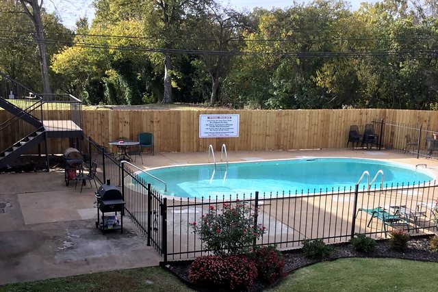 Swimming pool behind a black iron fence with the grill area and courtyard