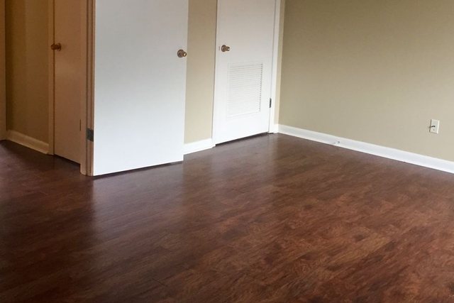 Bedroom in Unit 203 with dark wood-look flooring, closet doors, and a ceiling fan