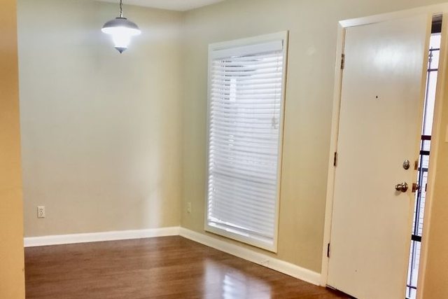 Living and dining area in Unit 210 with glossy dark wood-look flooring and a pendant light