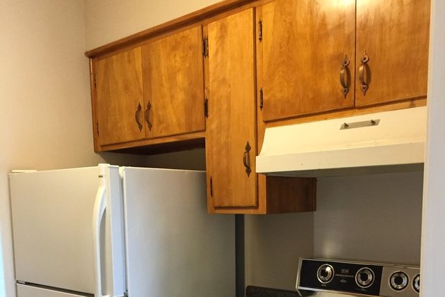 Updated kitchen with wood cabinets, range hood, and white appliances