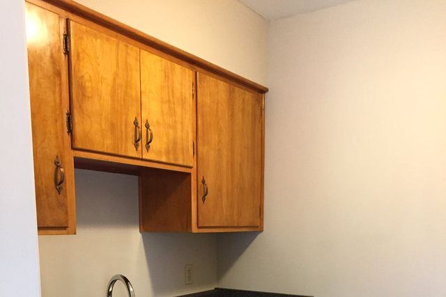 Updated kitchen with wood cabinets, dark countertop, and white dishwasher