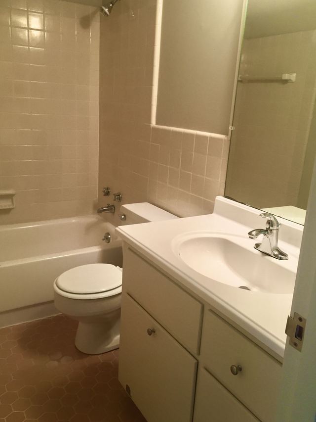 Classic bathroom with original tile tub surround, white vanity, and a large mirror