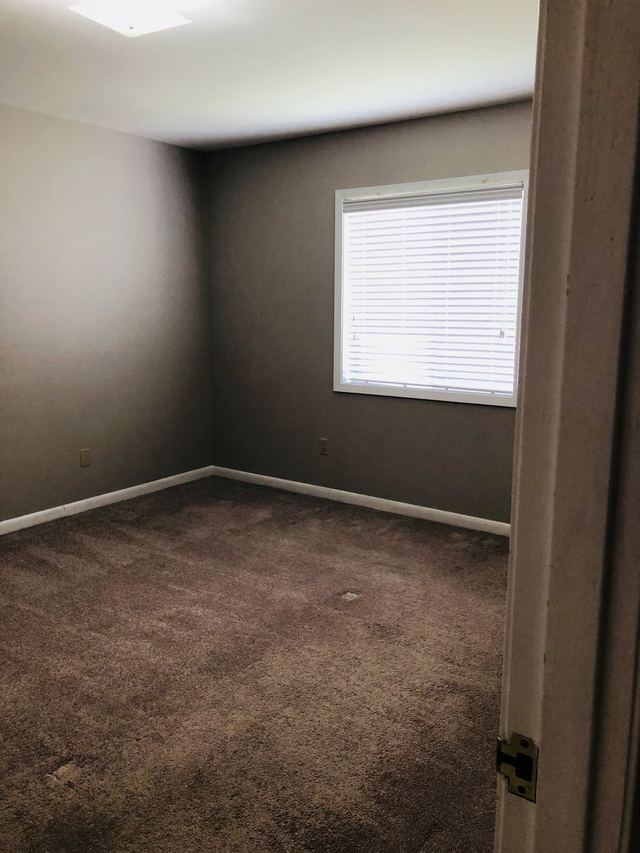 Bedroom in Unit 102 with gray walls and a large window with blinds