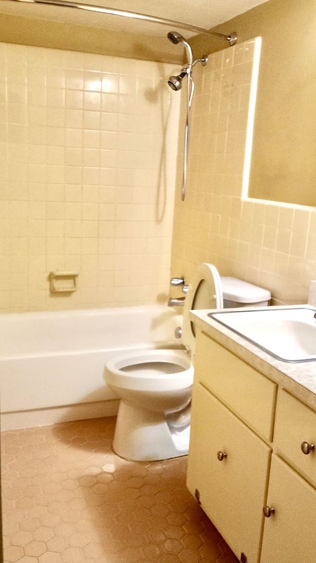 Bathroom in Unit 210 with a white tub, clean tiled surround and grout, and vanity